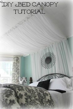 a large bed sitting under a canopy in a bedroom next to a window with curtains on it