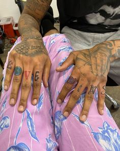 two hands with tattoos on them sitting next to each other