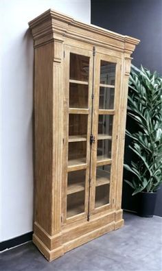 a tall wooden cabinet next to a potted plant