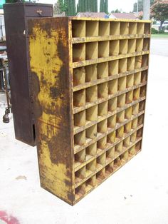 an old yellow metal box sitting on the side of a road