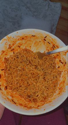 a person holding a bowl of noodles with chopsticks