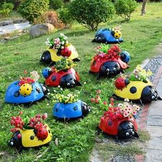 colorful ladybug planters sitting on the ground in front of some grass and flowers