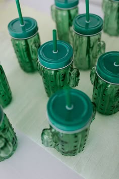 many green cups with lids and straws on a table