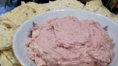 a white bowl filled with pink dip surrounded by tortilla chips on a table