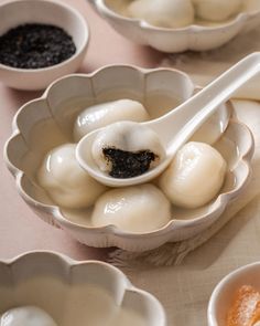 small bowls filled with dumplings and sauces on a white tablecloth covered table