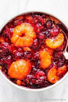 cranberry sauce with oranges and cherries in a pot on a marble surface