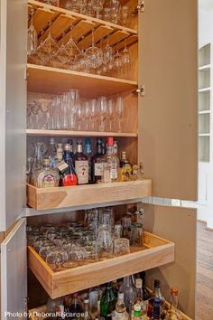 an open cabinet filled with lots of bottles and glasses