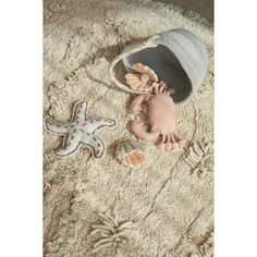 a baby is laying on the floor next to some starfish and a hat,