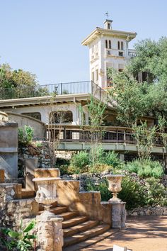 an old building with steps leading up to it and trees in the foreground, on a sunny day