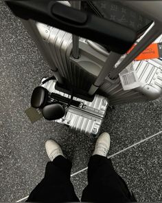 a person standing next to a piece of luggage on top of a floor with their feet up