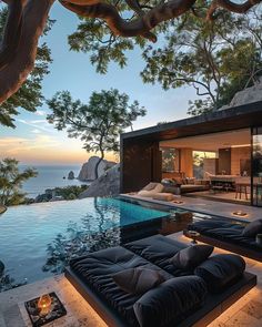 an outdoor living area with couches and tables next to the swimming pool at dusk