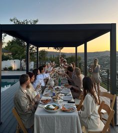 a group of people sitting at a long table with plates of food in front of them