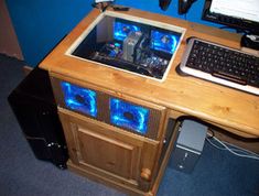 a wooden desk with a computer on top of it and a keyboard next to it