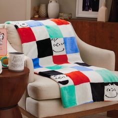 a chair with a blanket on top of it next to a coffee cup and book