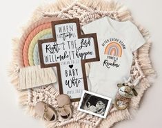 baby clothes and other items are laid out on a white blanket with a rainbow in the background