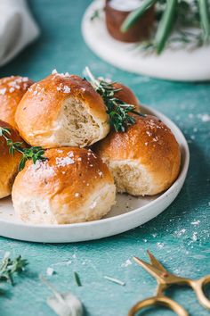 several rolls on a plate with sprigs of rosemary