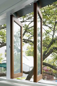 an open window on the side of a building with trees in the backround