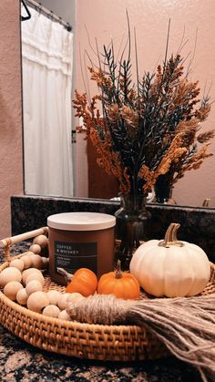 an arrangement of pumpkins and gourds in a basket on a counter top