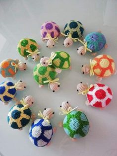 small crocheted turtle ornaments are arranged in a circle on a white table top