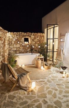 a bathroom with stone walls and flooring next to a bathtub filled with candles