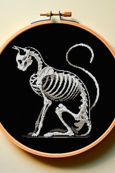 a cross - stitch skeleton cat sitting on the ground in front of a black background