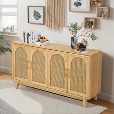 a wooden cabinet with wicker doors in front of a window and pictures on the wall