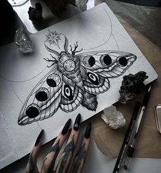 a person's hand with black and white tattoos next to a drawing of a moth