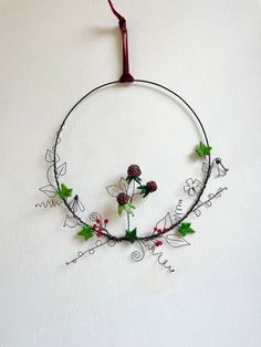 a wire wreath with flowers and leaves hanging on the wall