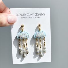 a pair of earrings is shown in front of a card with the text flower clay designs handmade jewelry