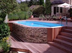 an above ground pool with steps leading up to it and a stone wall around it