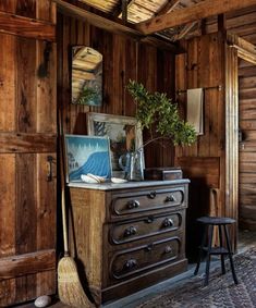 a room with wooden walls and an antique dresser in the corner, next to a small potted plant