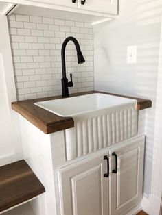 a white kitchen sink sitting under a faucet next to a wooden counter top