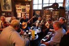 a group of men sitting around a table with guitars and beer glasses in front of them