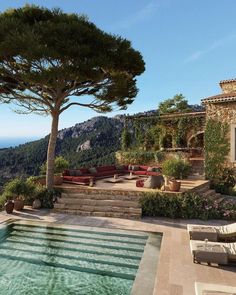 an outdoor swimming pool surrounded by greenery and stone steps leading up to the top of a hill