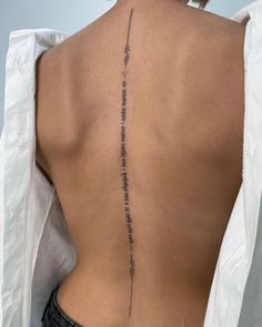 the back of a woman's lower back tattoo with writing on her left side