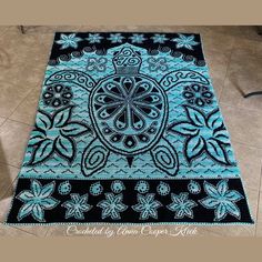 a blue and black rug with an intricate design on the floor in front of a tile floor