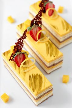 three pieces of cake with strawberries on top and yellow icing around the edges