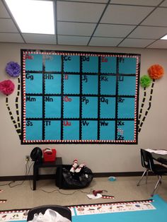 a bulletin board with letters and numbers on it in an office cubicle decorated with paper pom poms