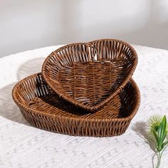 two wicker baskets sitting on top of a white tablecloth next to a flower