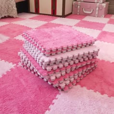 pink and white rugs stacked on top of each other in front of a bed