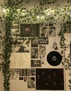 a wall covered in photos and plants next to a clock with vines growing on it