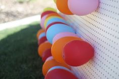 a row of colorful balls on the side of a wall with grass in the background