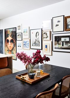 a dining room table with flowers and pictures on the wall