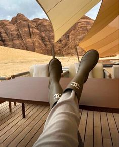 a person's feet resting on a table with mountains in the background