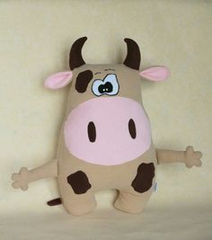 a stuffed cow with big eyes and brown spots on it's face, standing in front of a wall