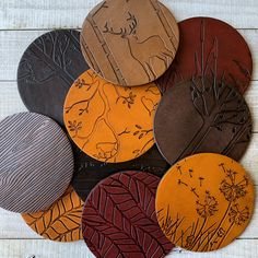 a bunch of coasters that are sitting on top of a wooden table with leaves