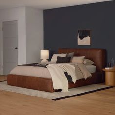 a large bed in a room with blue walls and wooden floors, along with a rug on the floor