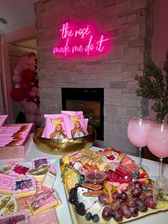 a table topped with lots of pink and gold desserts next to a fire place