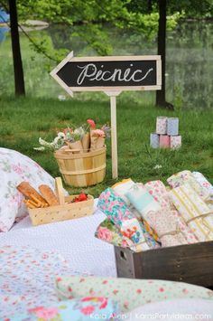 an outdoor picnic with bread and flowers on the grass near a sign that says picnic