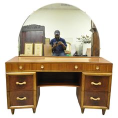 a man is taking a photo in front of a mirror on a desk with drawers